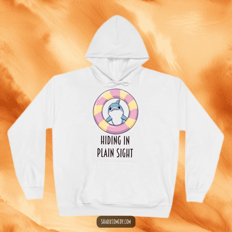 Funny shark peeking from behind an inflatable ring, depicted on a soft hoodie, ideal for casual, humorous wear.