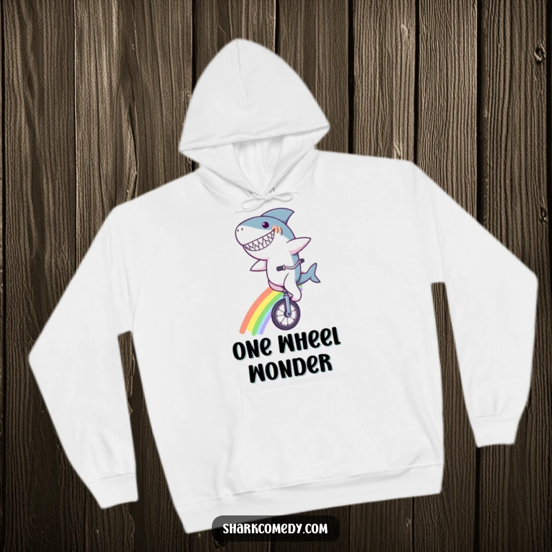 Funny shark character hoodie, with a goofy grin, riding a unicycle across a vibrant rainbow, a warm and humorous design for dreamers.